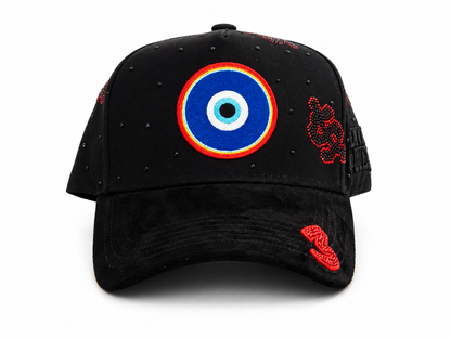 A black baseball cap featuring a prominent blue, red, and white evil eye patch on the front, with red embroidered details on the side and brim, set against a plain white background.