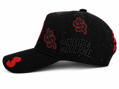 A black baseball cap featuring red rhinestone-embellished money signson the front panels and brim, with a black arched 'LA ENVIDIA NO DUEERME' text on the side and red rhinestone accents on the brim.
